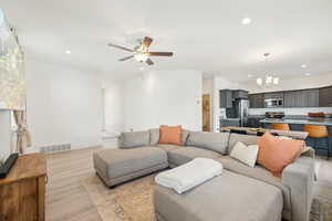 Living room featuring light hardwood / wood-style floors and ceiling fan with notable chandelier