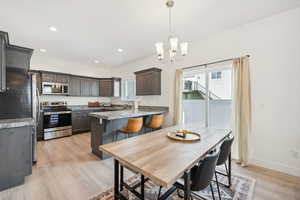 Dining space with light wood-type flooring, a notable chandelier, and a healthy amount of sunlight