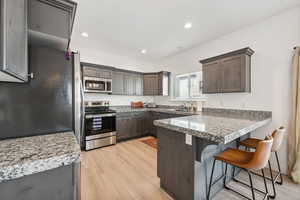 Kitchen featuring sink, light hardwood / wood-style floors, a breakfast bar area, stainless steel appliances, and kitchen peninsula