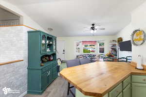 Interior space featuring butcher block counters, light hardwood / wood-style flooring, green cabinets, lofted ceiling, and ceiling fan