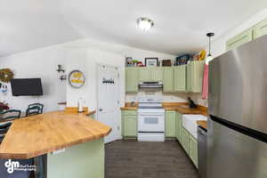 Kitchen with stainless steel appliances, butcher block countertops, lofted ceiling, dark hardwood / wood-style flooring, and green cabinetry