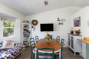 Dining room featuring vaulted ceiling and dark wood-type flooring