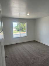 Empty room with a textured ceiling and carpet floors