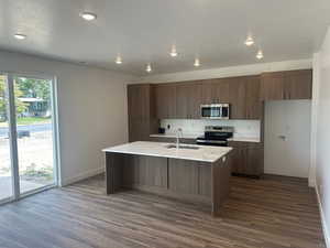 Kitchen featuring appliances with stainless steel finishes, an island with sink, sink, and dark hardwood / wood-style floors