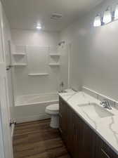 Full bathroom featuring vanity, toilet, hardwood / wood-style floors, and washtub / shower combination