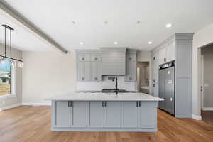 Kitchen featuring a center island with sink, light hardwood / wood-style floors, high end fridge, and gray cabinets