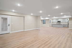 Unfurnished living room with light wood-type flooring and sink