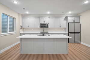 Kitchen featuring stainless steel appliances, an island with sink, and light hardwood / wood-style flooring