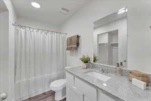 Full bathroom with vanity, toilet, hardwood / wood-style flooring, and shower / tub combo