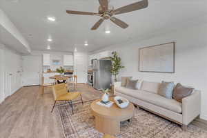 Living room with ceiling fan and light hardwood / wood-style floors