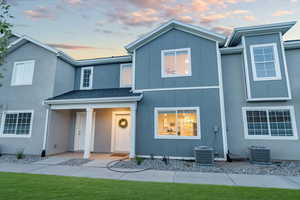 View of front of house with a yard and central air condition unit