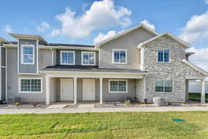 View of front of property with central air condition unit and a front yard