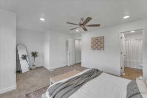 Bedroom featuring light colored carpet, ensuite bath, and ceiling fan