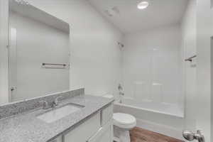 Full bathroom with vanity, toilet, hardwood / wood-style floors, and  shower combination