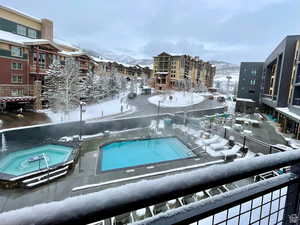 Snow covered pool with a mountain view and a hot tub