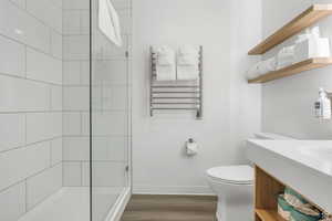 Bathroom with vanity, hardwood / wood-style floors, walk in shower, toilet, and radiator heating unit