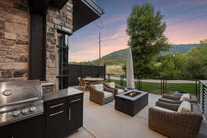 Patio terrace at dusk with a grill, an outdoor living space with a fire pit, and a mountain view