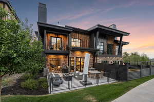 Back house at dusk featuring a balcony and outdoor lounge area