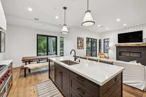 Kitchen with dark brown cabinets, light hardwood / wood-style flooring, sink, and hanging light fixtures