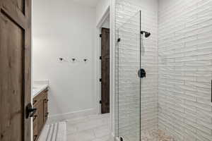 Bathroom featuring vanity, a tile shower, and tile patterned floors