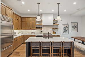 Kitchen featuring a center island with sink, a kitchen breakfast bar, appliances with stainless steel finishes, and decorative backsplash