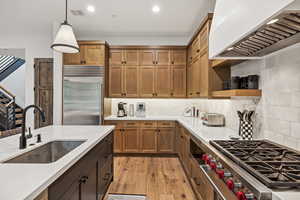 Kitchen with high end appliances, pendant lighting, tasteful backsplash, and sink