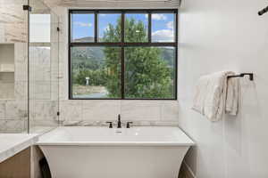 Bathroom featuring tile walls, shower with separate bathtub, and a healthy amount of sunlight