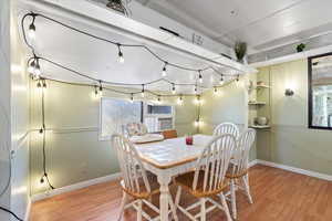 Dining area with cooling unit and light hardwood / wood-style flooring