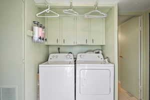 Washroom featuring light tile patterned floors, cabinets, and washer and dryer