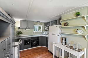 Kitchen with white refrigerator, sink, gray cabinetry, and dark hardwood / wood-style floors