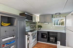 Kitchen featuring gray cabinetry, white appliances, and dark hardwood / wood-style flooring