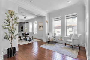 Sitting room with dark hardwood / wood-style floors and ornamental molding and ample amounts of light