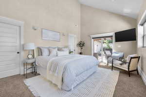 Owner's Suite bedroom with high vaulted ceiling and access to outside deck with hot tub