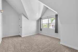 Upstairs bedroom featuring vaulted ceiling, light colored carpet and walk in closet