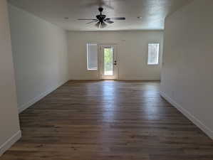 Empty room with a textured ceiling, ceiling fan, and dark hardwood / wood-style floors