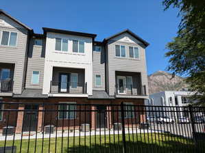 View of front of property featuring a mountain view, a balcony, and a front yard