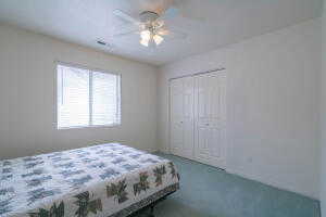 Carpeted bedroom with ceiling fan and a closet