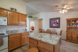 Kitchen with a center island, light hardwood / wood-style flooring, white appliances, lofted ceiling, and ceiling fan