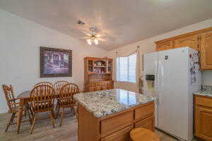 Kitchen featuring white fridge with ice dispenser, a kitchen island, ceiling fan, lofted ceiling, and light hardwood / wood-style floors