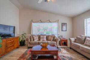 Living room with light hardwood / wood-style flooring, ceiling fan, and vaulted ceiling