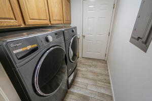 Clothes washing area featuring light hardwood / wood-style flooring, cabinets, and washing machine and clothes dryer