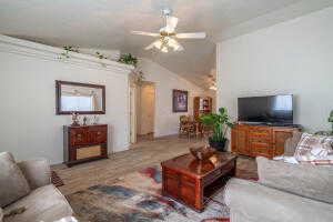 Living room with ceiling fan, wood-type flooring, and vaulted ceiling