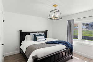 Bedroom with hardwood / wood-style flooring and an inviting chandelier