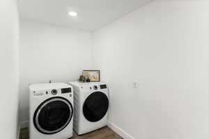 Washroom with hardwood / wood-style floors and washing machine and clothes dryer