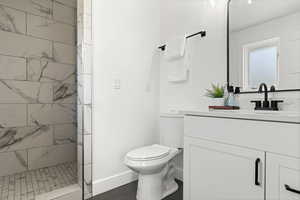 Primary Bathroom with tiled shower, vanity, and toilet