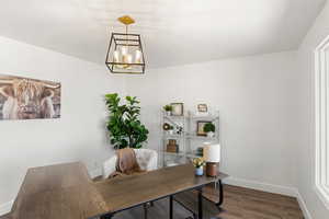 Home office featuring dark hardwood / wood-style floors and a chandelier