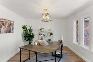 Office area featuring plenty of natural light, an inviting chandelier, and hardwood / wood-style flooring