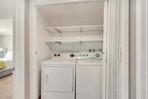 Laundry room featuring light colored carpet and washing machine and clothes dryer