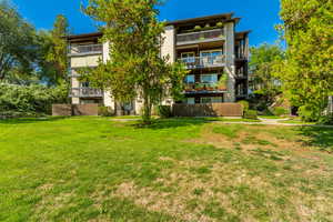 Rear view of property featuring a balcony and a lawn