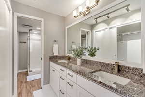 Bathroom with vanity, wood-type flooring, and a shower with door